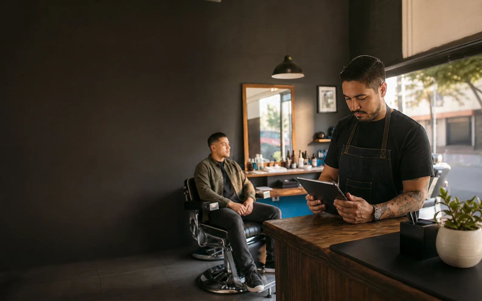 Barbero revisando reservas en una tablet dentro de una barbería moderna en México